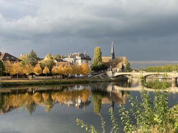 Reflection of buildings and trees in lake against sky