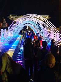 People in illuminated ferris wheel at night