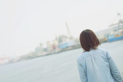 Rear view of woman with umbrella against sky