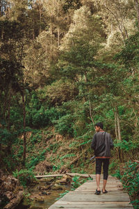 Rear view of man walking on footpath in forest