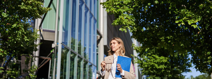 Low angle view of woman standing against trees