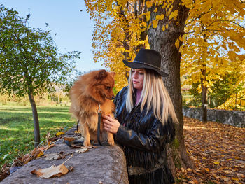 Woman with dog sitting in park during autumn