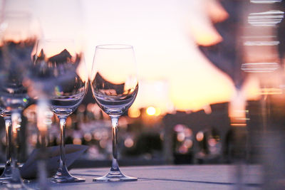 Close-up of wineglasses on table during sunset