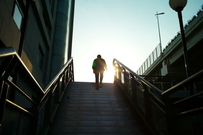 Rear view of man walking on footbridge