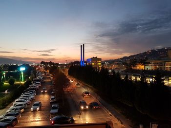 Vehicles on illuminated road against sky at night