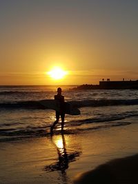 Silhouette man on beach against sky during sunset