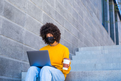 Young woman using mobile phone while sitting on staircase