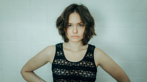 Portrait of young woman standing against wall