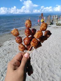 Close-up of hand holding ice cream at beach against sky