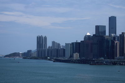 Sea by buildings against sky in city