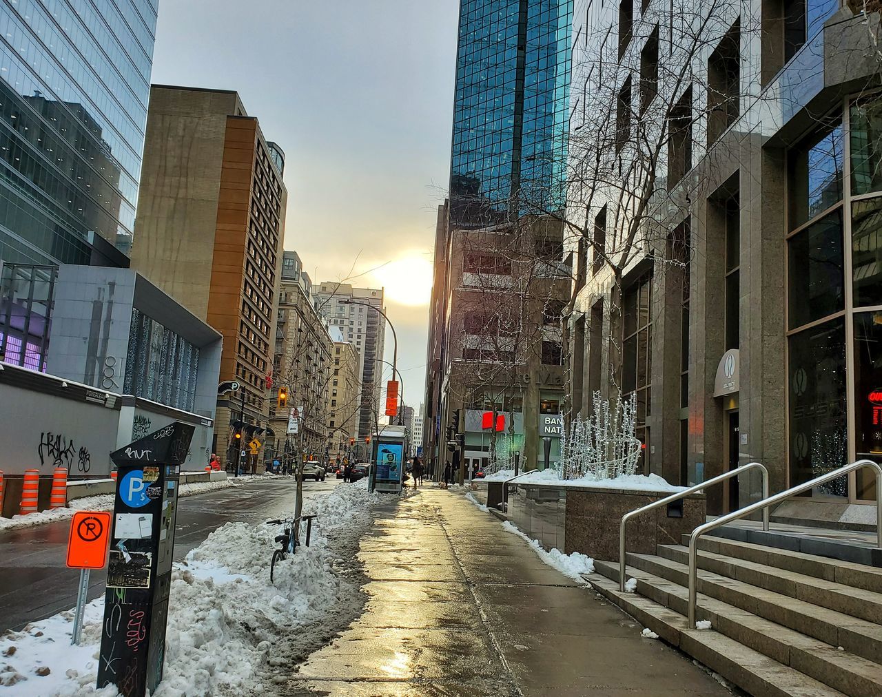 ROAD BY BUILDINGS AGAINST SKY IN CITY DURING WINTER