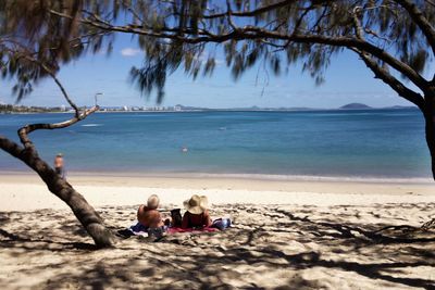 People sitting on beach against sea