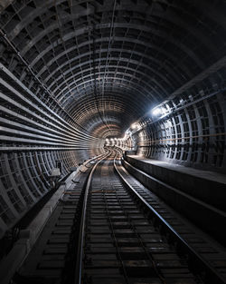 Railroad tracks in illuminated tunnel