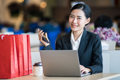 Portrait of young woman using phone on table