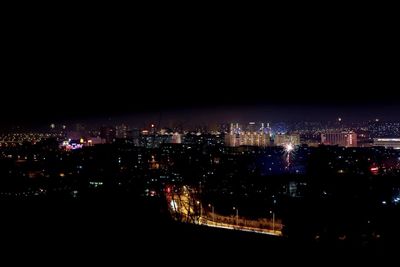 Illuminated cityscape against sky at night