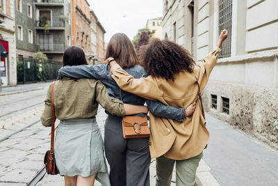 Friends walking with arm around at city street