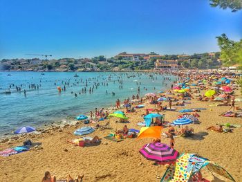 People on beach against clear blue sky