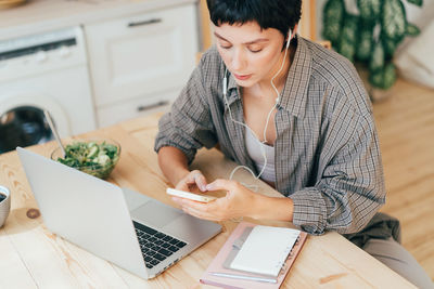 Young business woman sitting at the table working using gadgets.