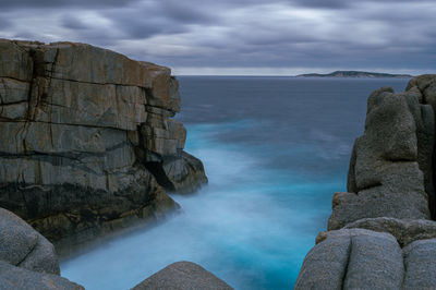 Panoramic shot of rocks by sea against sky