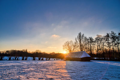 Scenic view of snow covered field against sky at sunset