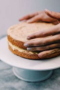 Close-up of hands holding sponge cake on stand