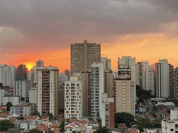 Buildings in city against sky during sunset