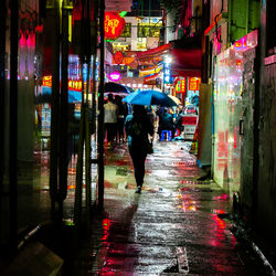 People walking on wet street during rainy season at night