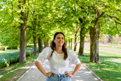 Portrait of smiling young woman standing against trees