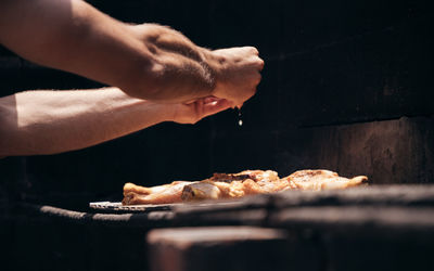 Close-up of man preparing food outside on the grill