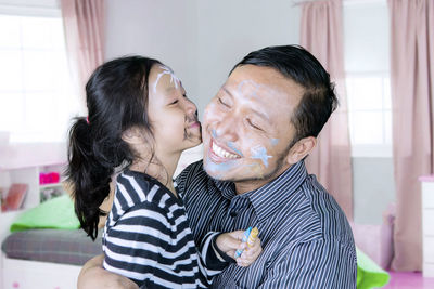 Close-up of happy girl kissing father while playing at home