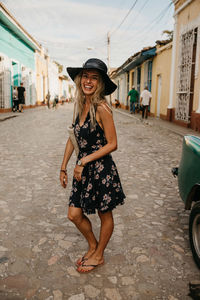 Full length portrait of smiling woman on street in city