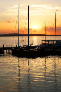 Silhouette sailboats in marina at sunset