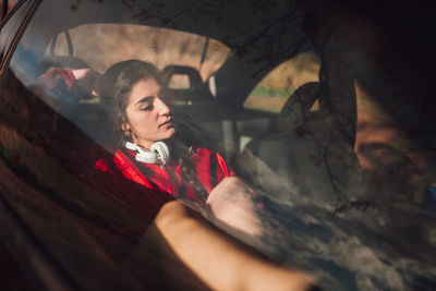 Young woman sitting in car seen through window