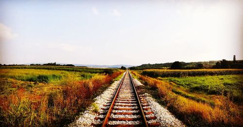 Railroad tracks on field against sky