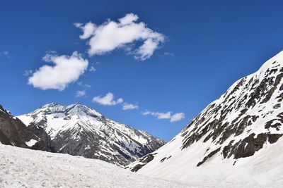 Low angle view of snowcapped mountains against blue sky