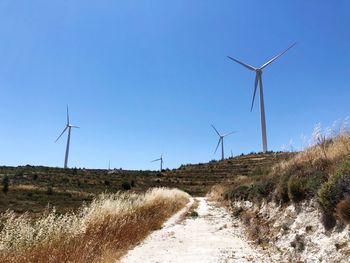 Wind turbines on field against clear sky