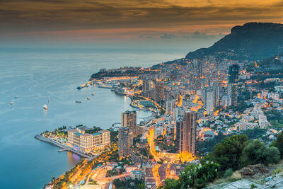 High angle view of townscape by sea against sky during sunset