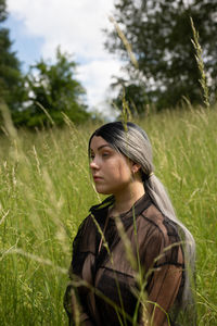 Portrait of young woman looking away on field