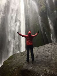 Rear view of man standing against waterfall