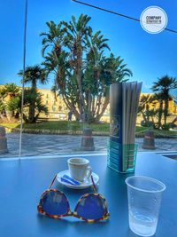 View of drinking glass on table by swimming pool against sky