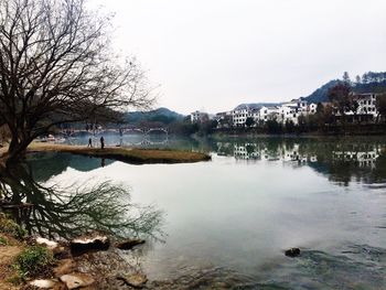 Scenic view of lake by town against sky during winter