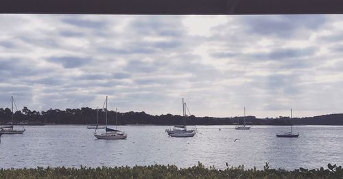 Boats in sea against cloudy sky