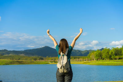 Rear view of woman standing in lake against sky