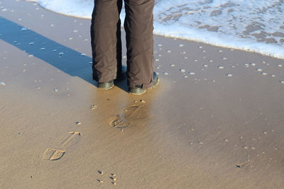 Low section of person standing on sand