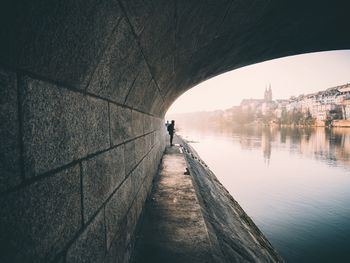 Side view of man under bridge over water