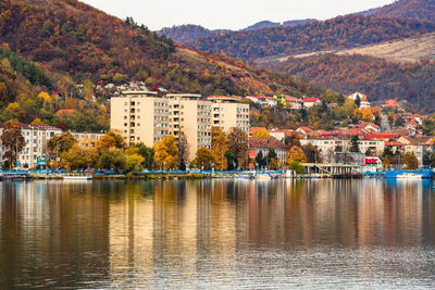 Lake by buildings against mountain during autumn