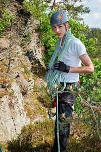 Portrait of boy holding rope while standing on rock