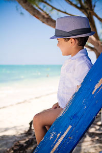 Little boy sitting on ladder at the beach watching caribbean waters