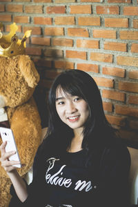 Portrait of a smiling young woman against wall