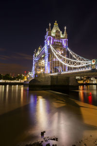 Illuminated bridge over river at night